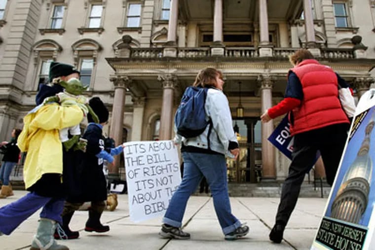 People carry signs as they walk in front of the New Jersey Statehouse where lawmakers were to debate over whether to legalize gay marriage on Monday in Trenton. (AP Photo/Mel Evans)