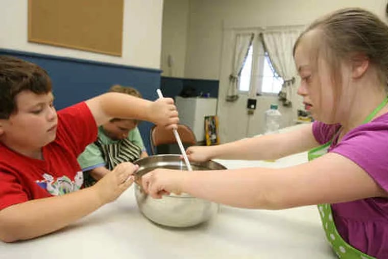 Kevin Flocco (left) and Annie Boyle work together as they stir their brownie mix. They are partof a cooking class run by KidsAhead, a program that helps autistic children build life skills.