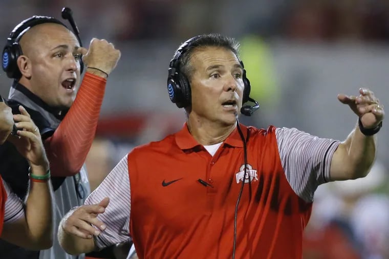 FILE – In this Sept. 17, 2016, file photo, Ohio State head coach Urban Meyer, right, and then-assistant coach Zach Smith, left, gesture from the sidelines during an NCAA college football game against Oklahoma in Norman, Okla. Ohio State expects to open fall camp as scheduled on Friday, Aug. 3, 2018, but without coach Urban Meyer. Meyer was put on administrative leave on Wednesday, Aug. 1 over the handling of a longtime assistant who has been accused of domestic violence. Co-offensive coordinator Ryan Day will be running the team while Ohio State investigates claims that Meyer's wife knew about 2015 allegations of abuse against former Buckeyes assistant Zach Smith, who was fired last week. (AP Photo/Sue Ogrocki, File)