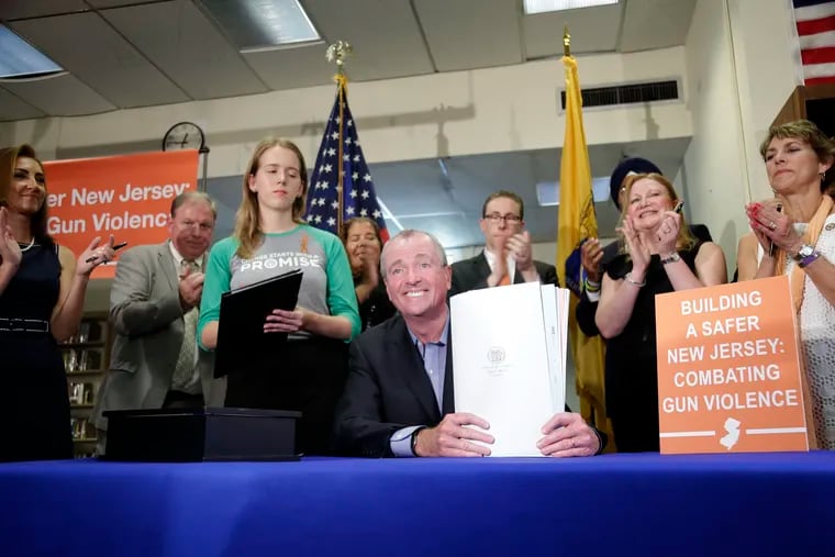 New Jersey Gov. Phil Murphy, center, poses for a picture with gun control bills he signed during a ceremony in Berkeley Heights in July.