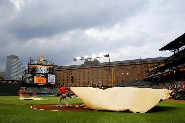 Groundskeepers cover home plate with a tarp during a rain delay before a baseball game between the Philadelphia Phillies and the Baltimore Orioles, Tuesday, May 15, 2018, in Baltimore. (