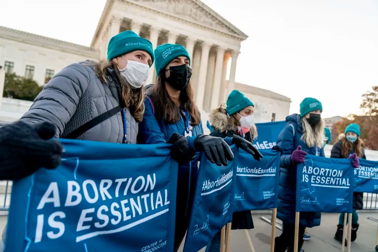 Abortion rights advocates hold signs that read "Abortion is Essential" as they demonstrate in front of the U.S. Supreme Court on Wednesday.