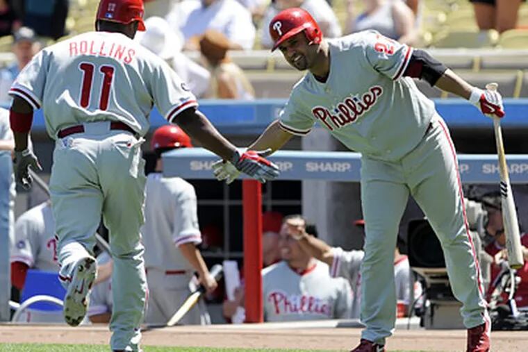 Jimmy Rollins gets congratulations from Placido Polanco after hitting a solo home run to lead off the game. (Chris Pizzello/AP)