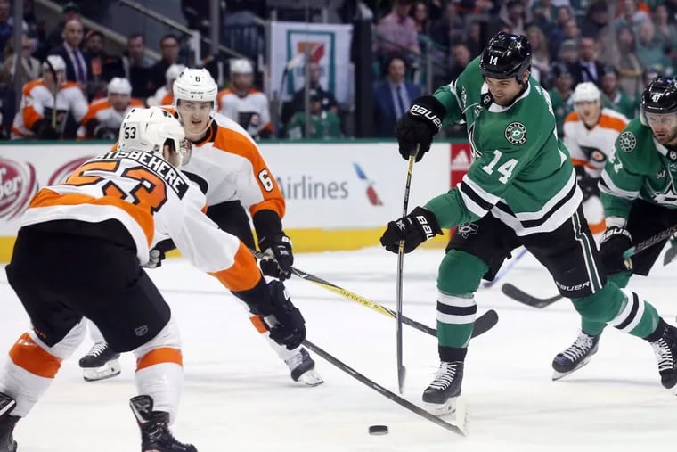 Stars left winger Jamie Benn (14) gets a shot on goal as Flyers defenseman Shayne Gostisbehere (53) defends him during the first period Tuesday in Dallas.