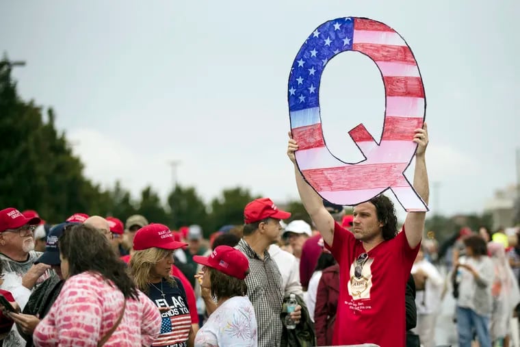 David Reinert holding a Q sign waits in line with others to enter a campaign rally with President Donald Trump in Wilkes-Barre, Pa. QAnon is a far-right conspiracy theory forged in a dark corner of the internet is creeping into the mainstream political arena.