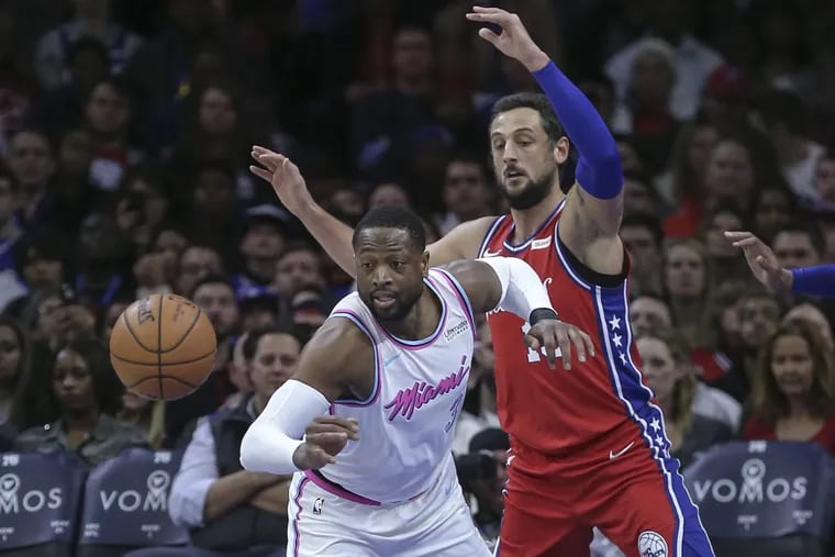 The Sixers' Marco Belinelli and the Heat's Dwyane Wade eyeing a loose ball during the teams’ meeting Feb. 14.