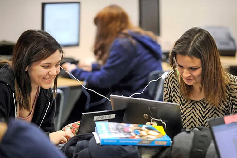 Sophomores Hope Rorer (left) and Lexi Karp share a headphone in the classroom of Nicole Roeder, a cyber program teacher. (Tom Gralish/Staff)
