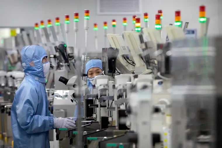 Employees wearing protective equipment work at a semiconductor production facility for Renesas Electronics during a government organized tour for journalists in Beijing, on May 14, 2020.