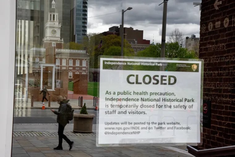 Independence Hall is reflected in the glass door of the closed Independence Visitor Center.