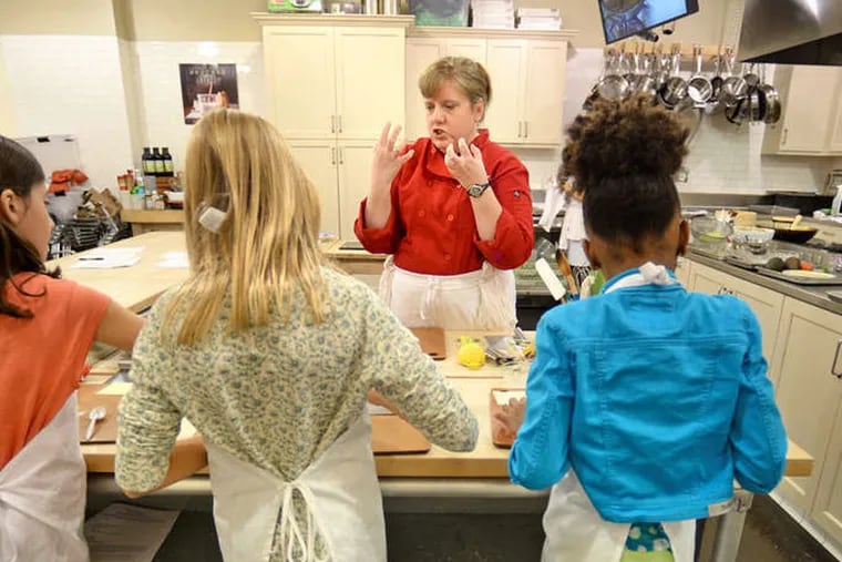 Chef Angie Lee talks about food during a class with young cooks (from left) Anna Welsh, Norah Hendrickson, and Kennedy Farr at the Sur La Table store in the Court at the King of Prussia Mall. ( TOM GRALISH / Staff Photographer )