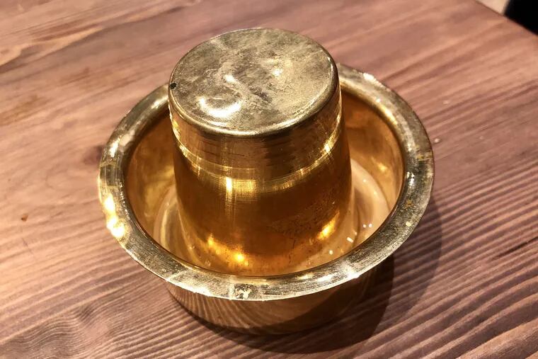 The coffee at Amma's South Indian Cuisine is served upside down in a Madras-style brass tumbler set inside a metal saucer called a dabarah.