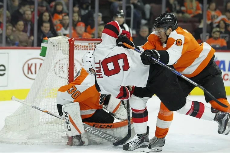 Robert Hagg (right)  clears Devils’ forward Taylor Hall from in front of the net in the Flyers’ 5-4 loss to New Jersey in a shootout on Tuesday.
