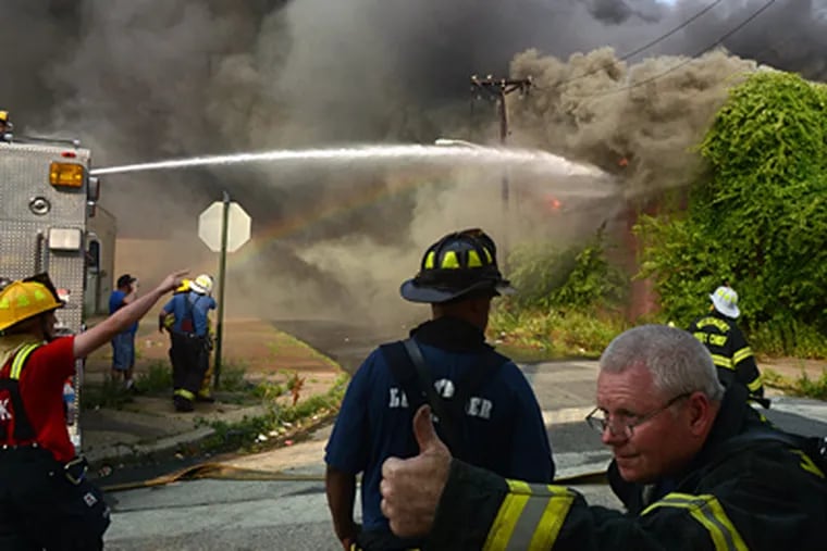 Firefighters move hoses into place while fighting the Camden fire. Blistering heat and wind Thursday caused it to spread quickly, a union official said. (Tom Gralish / Staff Photographer)