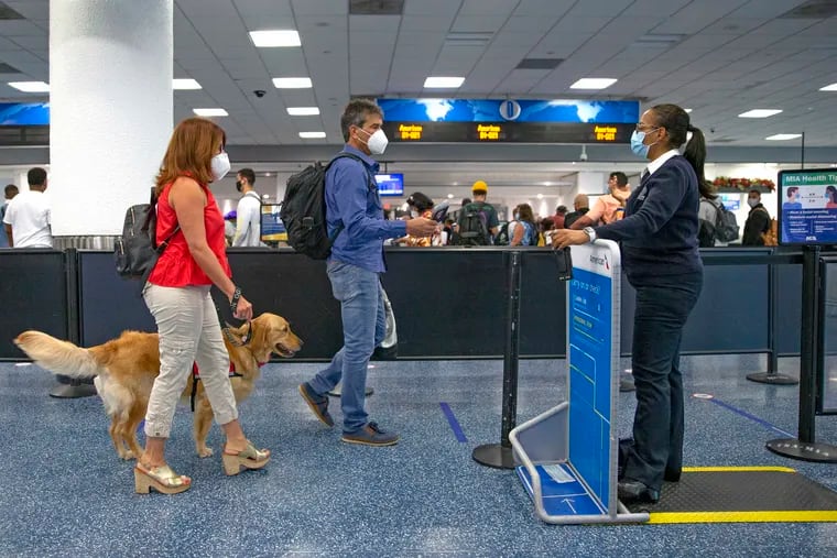 Travelers wearing protective face masks walked through a security checkpoint at Concourse D at the Miami International Airport on Nov. 22. Florida on Thursday became the third state to identify a case of the coronavirus variant first detected in the United Kingdom.