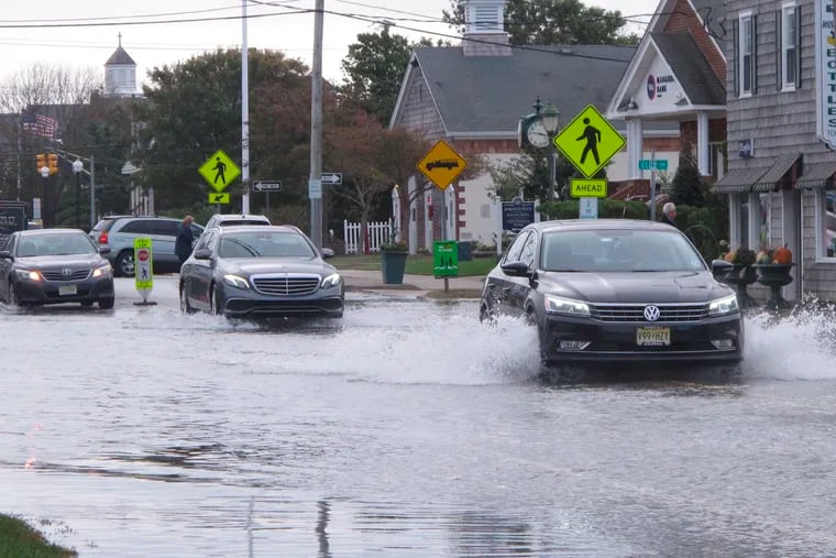 Cars kick up spray while driving through a flooded street in Bay Head, N.J., during a “sunny day” flood in 2019 caused by tides and rising sea levels.
