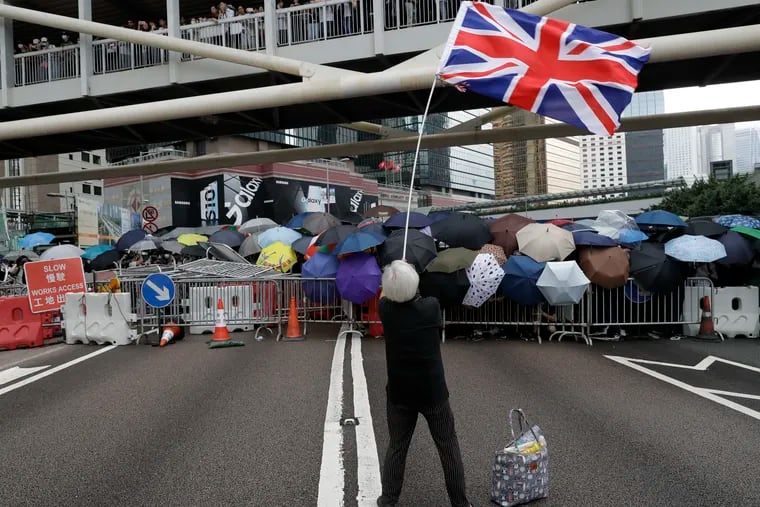 A protester waving the Union Jack joins other protesters using umbrellas to shield themselves outside the Legislative Council in Hong Kong on Wednesday.