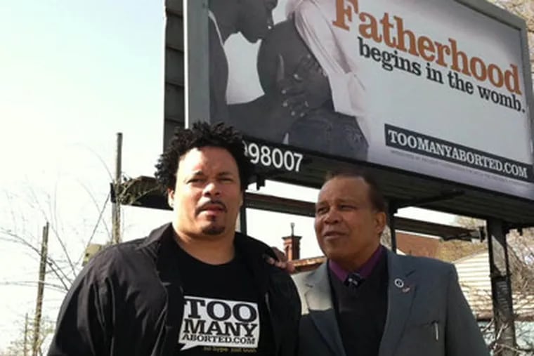 Ryan Bomberger (left) and Jimmie Hollis (both CQ)at pro-fatherhood, anti-abortion billboard in Camden. (Photo by Kevin Riordan)