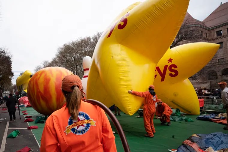 A volunteer shoulders a helium hose as balloons are inflated Wednesday, the day before the Macy's Thanksgiving Day Parade in New York.
