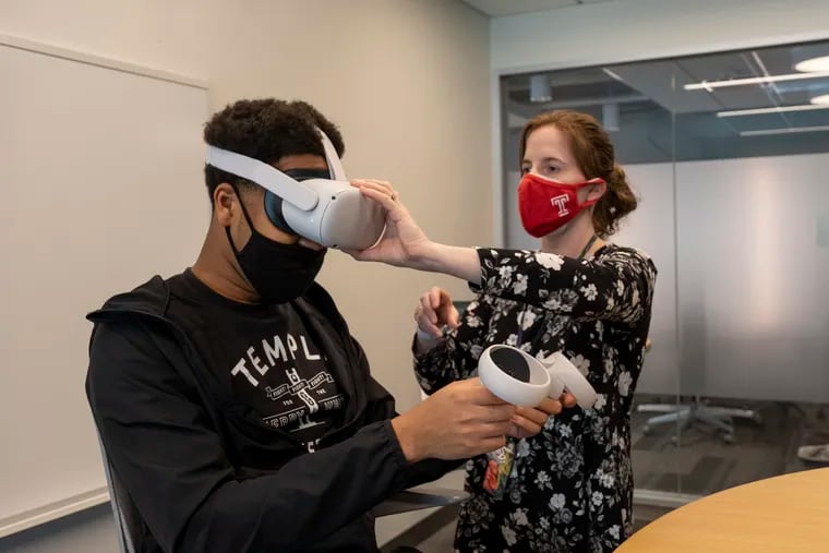 Carly Papenberg, director of Instructional Design at Temple University’s Fox School of Business, assists Lawrence Ukenye with the placement of his Oculus headset.