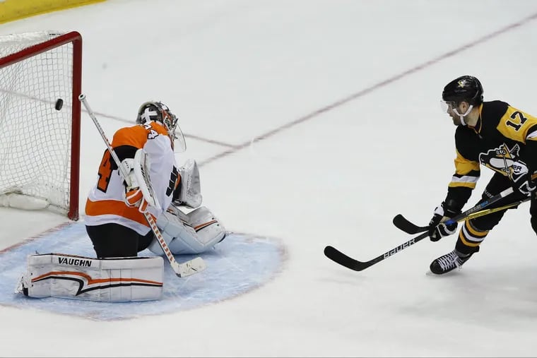 Pittsburgh’s Bryan Rust (17) deflecting the puck past Flyers goaltender Petr Mrazek for the overtime goal Sunday.
