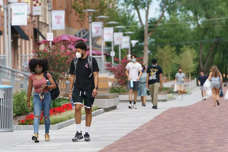 People wearing masks walk on campus at Temple University, where classes started Monday.