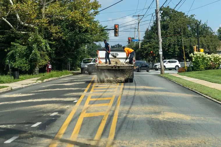 Workers shoveling sand on Lansdowne Avenue at Baily Road in Yeadon after a large oil spill occurred Wednesday.