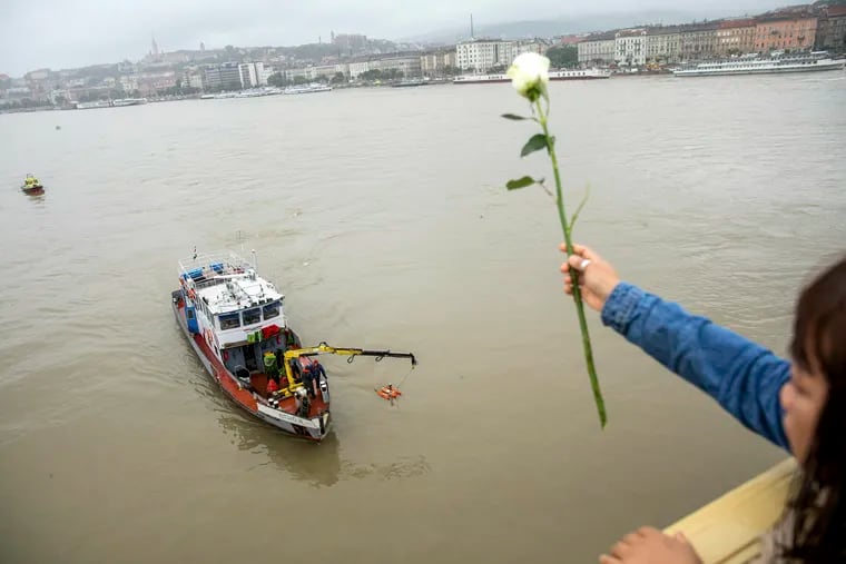 A woman throws a flower from the Margaret Bridge during a search operation on the River Danube in Budapest, Hungary, Thursday, May 30, 2019, following a collision of a hotel ship and a smaller cruise ship on the previous evening.