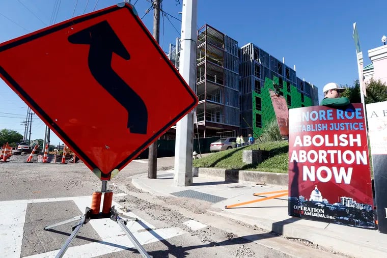 Abortion opponents stand outside the Jackson Women's Health Organization clinic, right, while construction on a hotel continues in Jackson, Miss., Wednesday, April 10, 2019. The clinic is the only medical facility that performs abortions in the state. The state legislature recently passed a law that would ban most abortions after a fetal heartbeat is detected, meaning as early as six weeks.