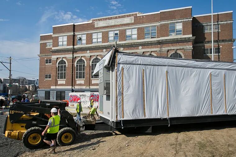 Workers move one of the modular units onto the grounds of Mid-Town Parish. The old building had to be demolished after water weakened its supports.
