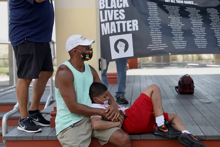 Tony Davenport (left), a city councilmember in Pleasantville, N.J., sits with his grandson Clifford Davenport, 10, during a Black Lives Matter rally on the boardwalk in Atlantic City, N.J., on Friday, Sept. 4, 2020. Rally organizer Steve Young had planned to paint "Black Lives Matter" on the boardwalk, but ultimately agreed instead to participate in a street painting event in front of the city's Civil Rights Garden, organized by Mayor Marty Small.
