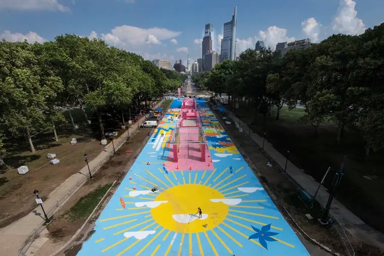 Artist Elise Stewart paints the sun on a ground mural painted for this year's pop-up urban beach, near Eakins Oval in Philadelphia, Pa. Monday, July 16, 2018. JOSE F. MORENO / Staff Photographer