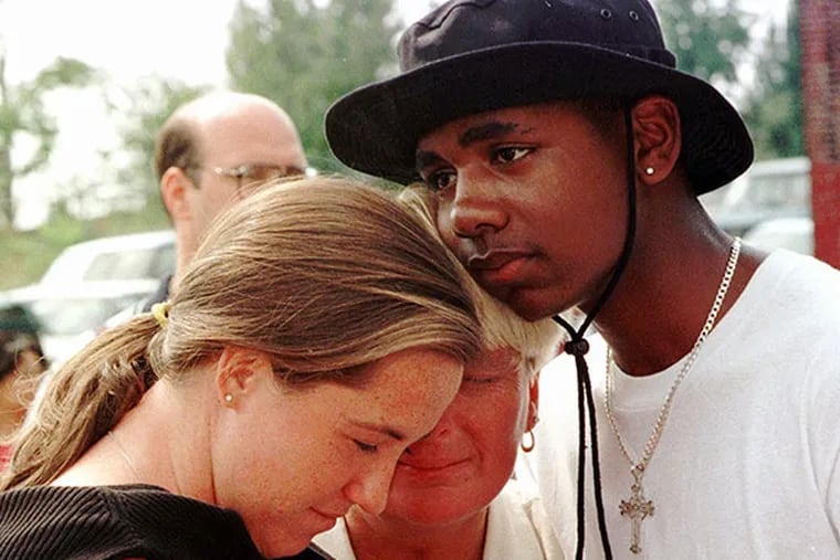 Slain athlete Aimee Willard's mother, Gail Willard (center), is embraced by Jason Culler (right) and a friend, Sunday, Sept. 13, 1998 in Philadelphia at the site where Aimee's body was found. (AP Photo/Jon Adams)
