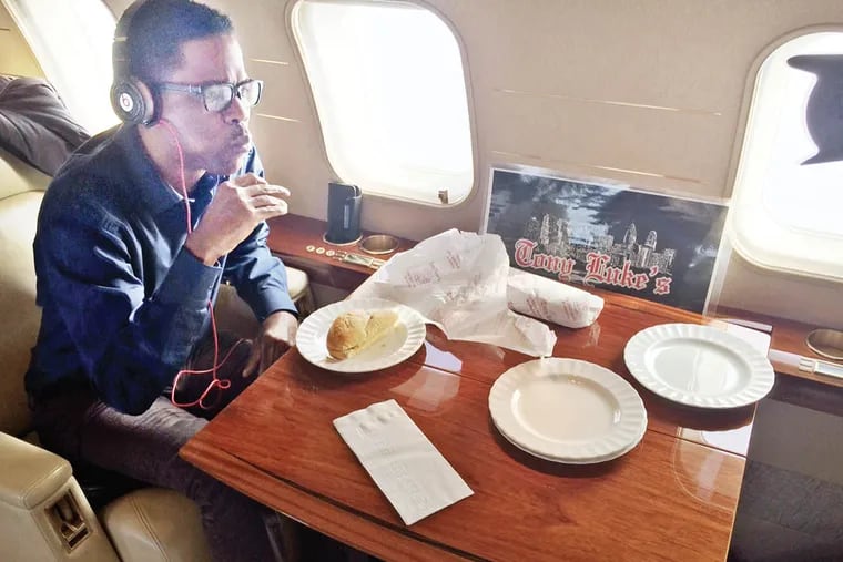 Chris Rock chows down on a Tony Luke's cheesesteak on his private plane after promoting his film 'Top Five.'