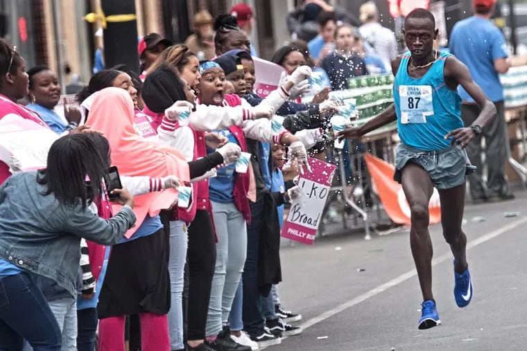 Daniel Kemoi gets water from volunteers as he leads the pack in the 2018 Blue Cross Broad Street Run on May 6, 2018. Kemoi, from Elkton, Md., was the winner of the race in 45 minutes and 43 seconds.