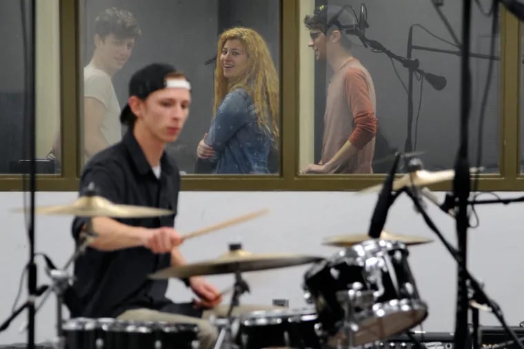 Senior Andrei Fritz plays drums while classmates behind the glass record him in instructor Jeff Hiatt's Project Audio Recording class at Rowan University.