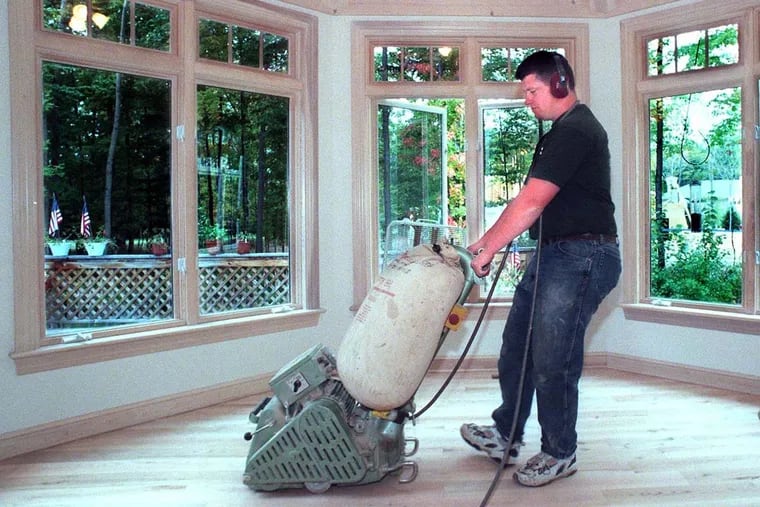 A belt sander being used to smooth a floor. Some stains can't be removed, even with sanding.