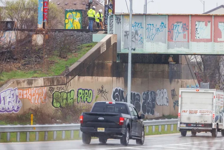 Two workers with safety jacks near the damaged railroad bridge over I-95 as seen from Luzerne near Richmond Street on Tuesday morning.