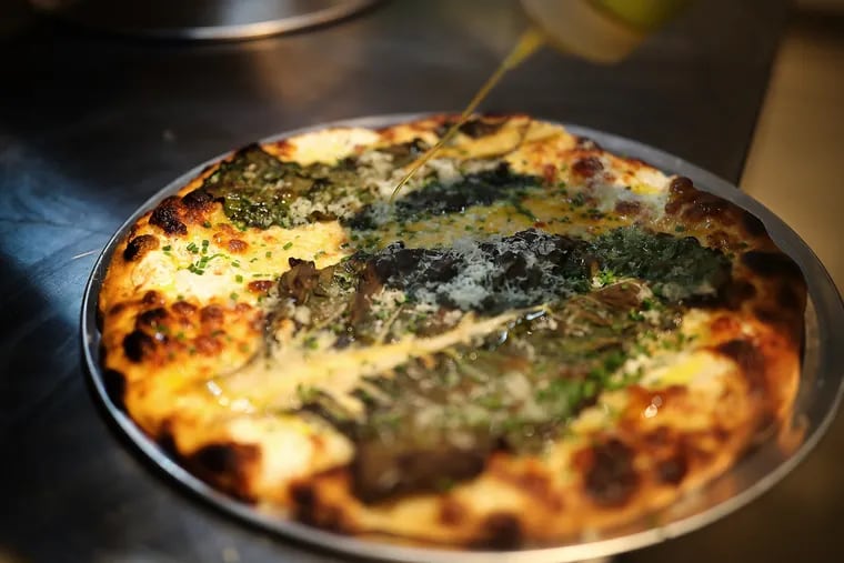 The Swiss chard pizza gets dressed with olive oil before being served at the new location of Pizzeria Beddia in Philadelphia.