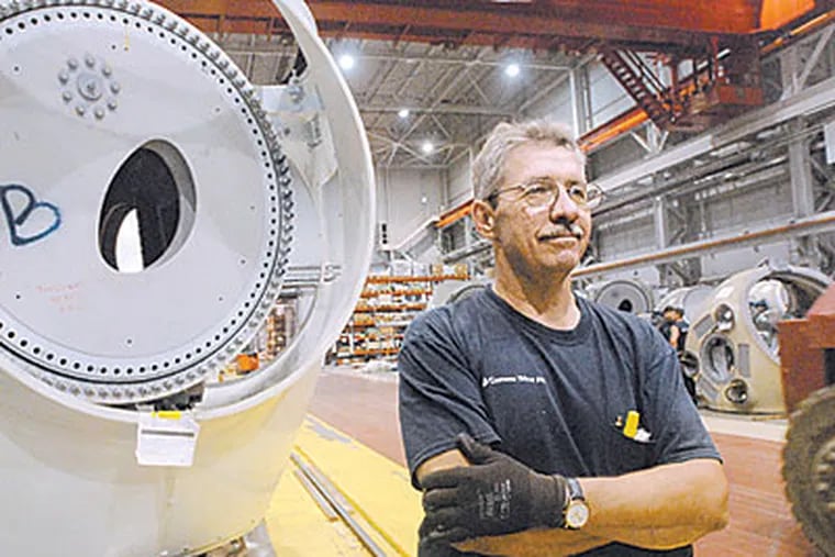At Gamesa, where he works, Jim Bauer stands in front of the hub of awind turbine. (April Saul/Inquirer)