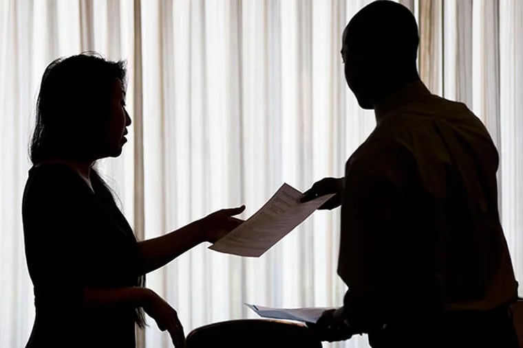 In this June 23, 2014 photo, recruiter Christina O, with New Western Acquisitions, left, takes Raheem Shaw's resumé during a job fair. Shaw is seeking a second job. The number of people seeking unemployment benefits, a proxy for layoffs, has fallen 10 percent since the first week of January. (AP Photo/Matt Rourke)