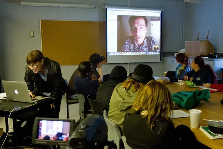 Fine Arts professor Elizabeth Demaray (left at computer) leads a SkypeOnArt session with Serbian artist Milos Tomic, on the screen. The class was being held in the Fine Arts Building, Rutgers University, Camden, on Nov. 4, 2013.  (DAVID M WARREN/Staff Photographer)