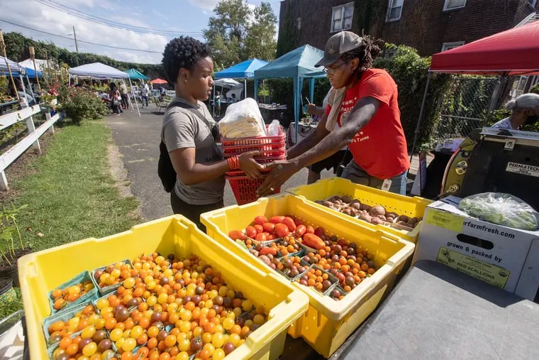 The second annual Black Farmers market in Southwest Philadelphia on Aug. 26, 2023. Chris Bolden-Newsome, (right) co-director of the farm at Bartram's Garden, is helped by a young woman as they load up their produce.