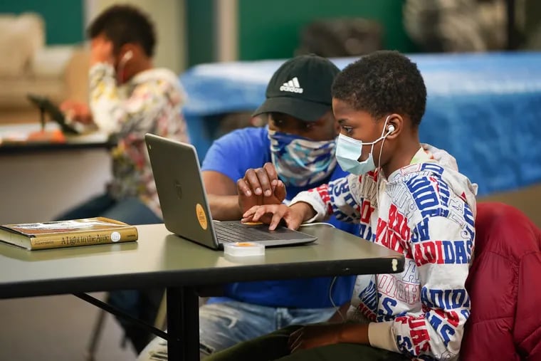 Daniel Padgett works on the computer with student Quamie Yasharahla, 10, at the Victorino Boys & Girls Club in Nicetown in April 2021. The club is one of Comcast's "Lift Zones," community centers that offer free WiFi to low-income residents who cannot access the internet at home.
