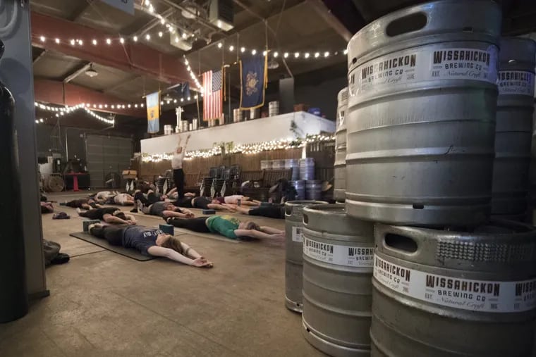 Participants practice yoga during a class in the brewery room at Wissahickon Brewing.