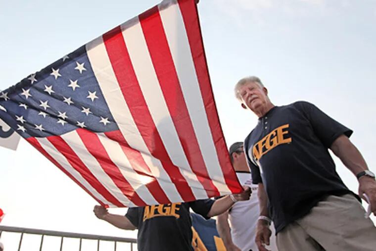 John Gage, right, the head of the American Federation of Government Employees, watches other union members unfurl one of their American Flags as they get ready to march in the Labor Day Parade on Monday. (Michael Bryant / Staff Photographer)
