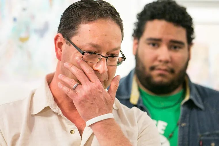 Paul Frame shows emotion while speaking about his husband, who has been detained by ICE, as Miguel Andrade, Communications Manager of Juntos, back right, looks on at a press conference at the William Way Center in Center City.