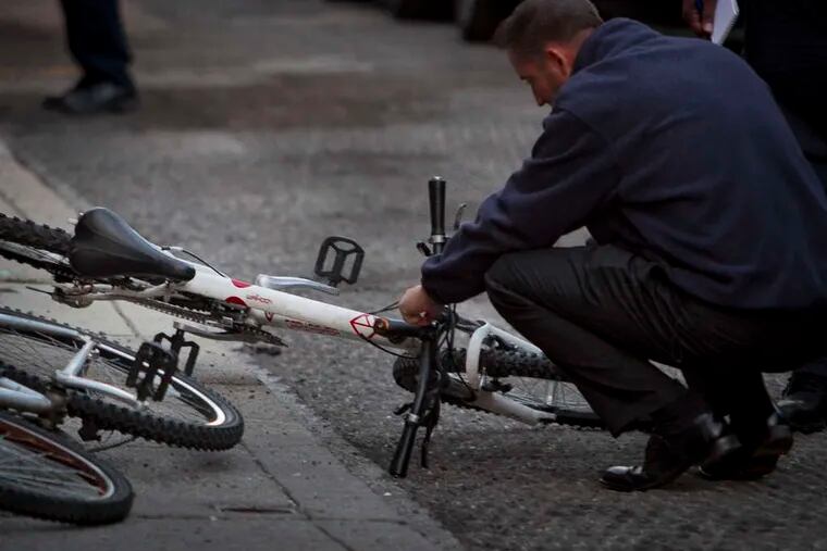 A detective examines a bicycle allegedly belonging to a man who killed a man early Thursday on Watkins Street.