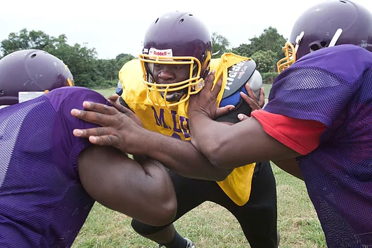 Martin Luther King Jr. H.S. lineman Dontae Angus breaks the blocks of
teammates Darvis Hurst-Rodney (left) and Frank Darden at practice. (David M Waren/Staff Photographer)