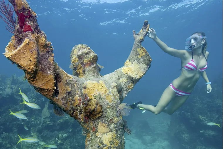 A snorkeler examines the Christ of the Abyss statue in the Florida Keys National Marine Sanctuary off Key Largo, Fla. The 4,000-pound statue is submerged in 25 feet of water.  Florida Keys News Bureau