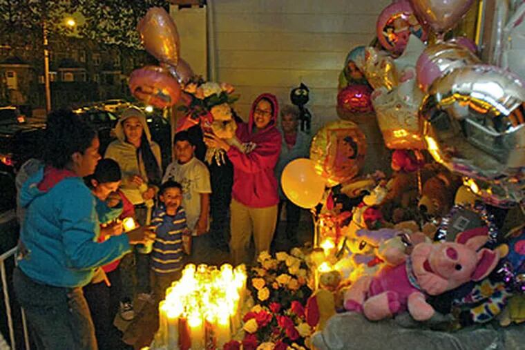 Neighbor Elizabeth Carrion brings a floral/balloon arrangement to the memorial set up on the front porch of Charleeni Ferreira, who died of child abuse earlier this week. Neighbors held a vigil Friday evening. (Clem Murray / Staff Photographer)